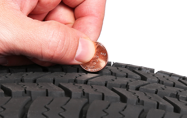 person checking tire tread depth with penny